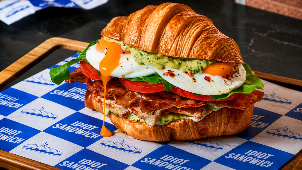 Croissant sandwich from Gordon Ramsay’s Idiot Sandwich pop-up in BGC, served with egg, bacon, greens, tomato, and sauce.