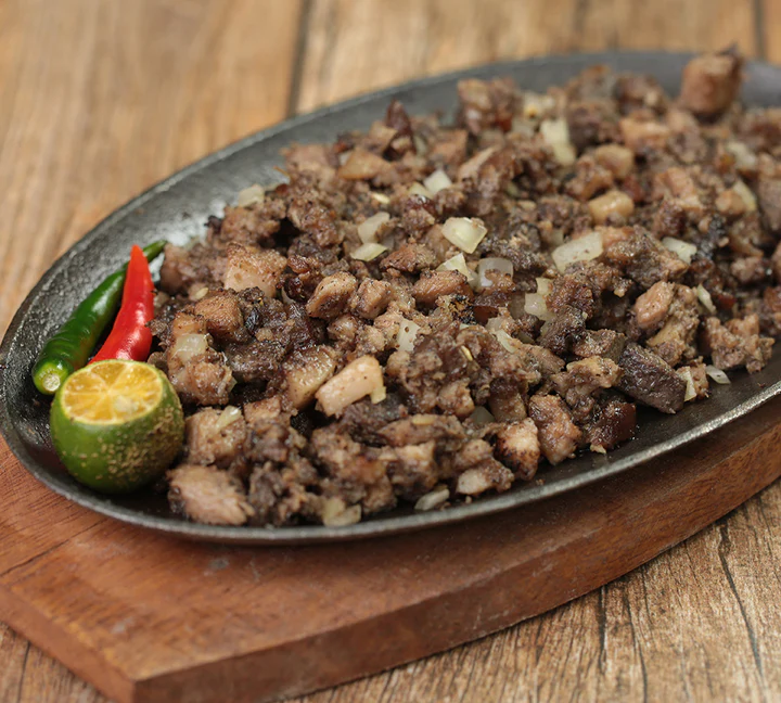 Plate of traditional Kapampangan pork sisig served on a sizzling platter with calamansi and chili